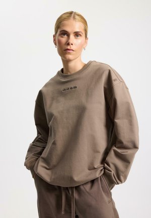 Hnedá mikina so zaobleným výstrihom, vo voľnom strihu a s rebrovanými manžetami. Má vyšívané logo "rethink studios" na hrudi. Mäkká textúra.