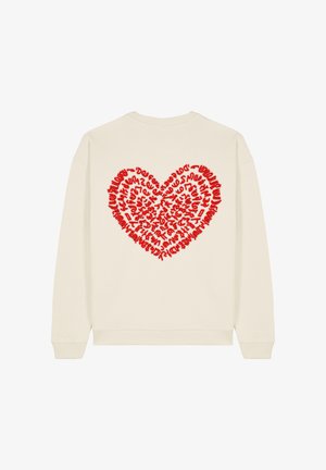 Pull crème avec un motif de cœur rouge texturé au dos, comportant diverses lettres et symboles à l'intérieur de la forme du cœur.