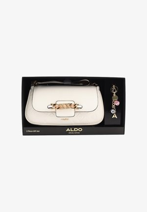 White faux leather handbag with gold hardware and embossed logo pattern, includes keychain with charms and a dice design, presented in a black box.