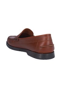 Zapatos de cuero marrón tipo slipper con punta redondeada, costuras visibles y suela de goma negra. Textura suave con acentos mínimos.