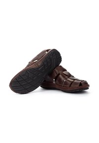 Braune Ledersandalen mit offenem Zehenbereich, ausgestattet mit geflochtenen Riemen und einer strukturierten Gummisohle für besseren Halt. Gestickte Details an den Kanten.
