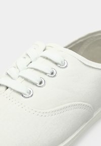 Hvide lærreds sneakers med seks snørrehuller, snørebåndsdesign og sølvmetal detaljer. Har en glat overflade og diskrete syninger.