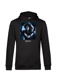 Felpa nera con cappuccio che presenta un'immagine centrata di una donna che danza in un vestito scuro, con figure sfocate sullo sfondo, e la scritta "Mercoledì" sottostante.