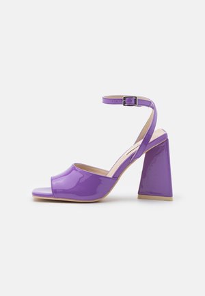 Lila Lackleder Sandale mit offenem Zehenbereich, hohen Absätzen, Knöchelriemen und silberner Schnalle, Blockabsatz und brauner Sohle.