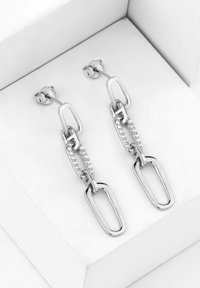 Silverörhängen med förlängd länkdesign, prydda med klara stenar för extra detalj. Visas på en vit dämpad yta.