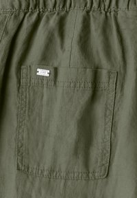 Olivgröna shorts med en rynkad midja och en bakfick. Har en etikett som säger "STREET ONE STUDIO." Mjukt, lätt material.