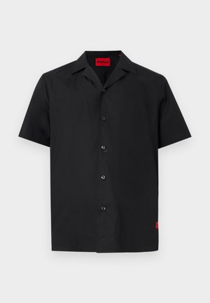 Μαύρο πουκάμισο με κοντό μανίκι, κουμπιά, γιακά τύπου camp, με κόκκινη ετικέτα "HUGO" στο εσωτερικό του λαιμού και μικρή κόκκινη ταμπέλα στο κάτω μέρος.