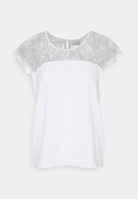 Weiße Bluse mit kurzen Ärmeln, die eine durchscheinende Spitzenpartie und einen strukturierten Körper aufweist. Schlüsselkopfverschluss auf der Rückseite, fließende Form und weicher Stoff.