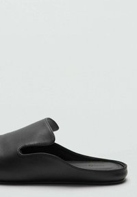 Scarpa nera in pelle senza lacci con schienale aperto e dettaglio a taglio nella parte superiore. Texture liscia, design minimalista, suola piatta.