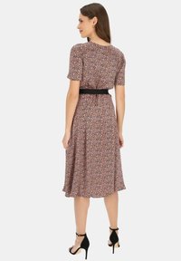 Sukienka w kwiatowy wzór z krótkimi rękawami, czarnym paskiem w talii i rozkloszowanym dołem. Kolory to różowy, fioletowy i żółty na ciemnym tle.