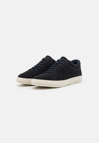 Tenisi din suede bleumarin, cu un design low-top, închidere cu șireturi și talpă din cauciuc off-white, având branding subtil pe toc.