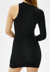 Robe noire côtelée avec un design asymétrique à une seule épaule, une manche longue d'un côté, une silhouette ajustée et une longueur mi-cuisse.