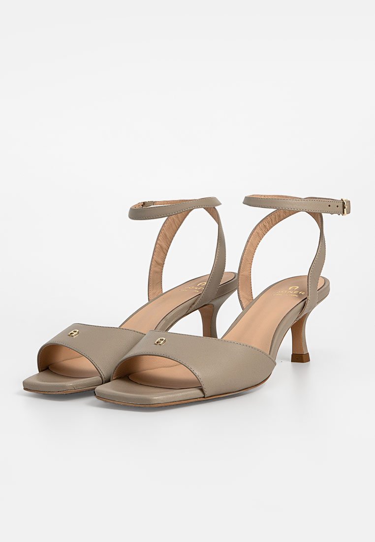 Sandales à talons beiges avec un bout ouvert, une bride à la cheville et un petit accent doré. Tige en cuir lisse et semelle intérieure ergonomique.