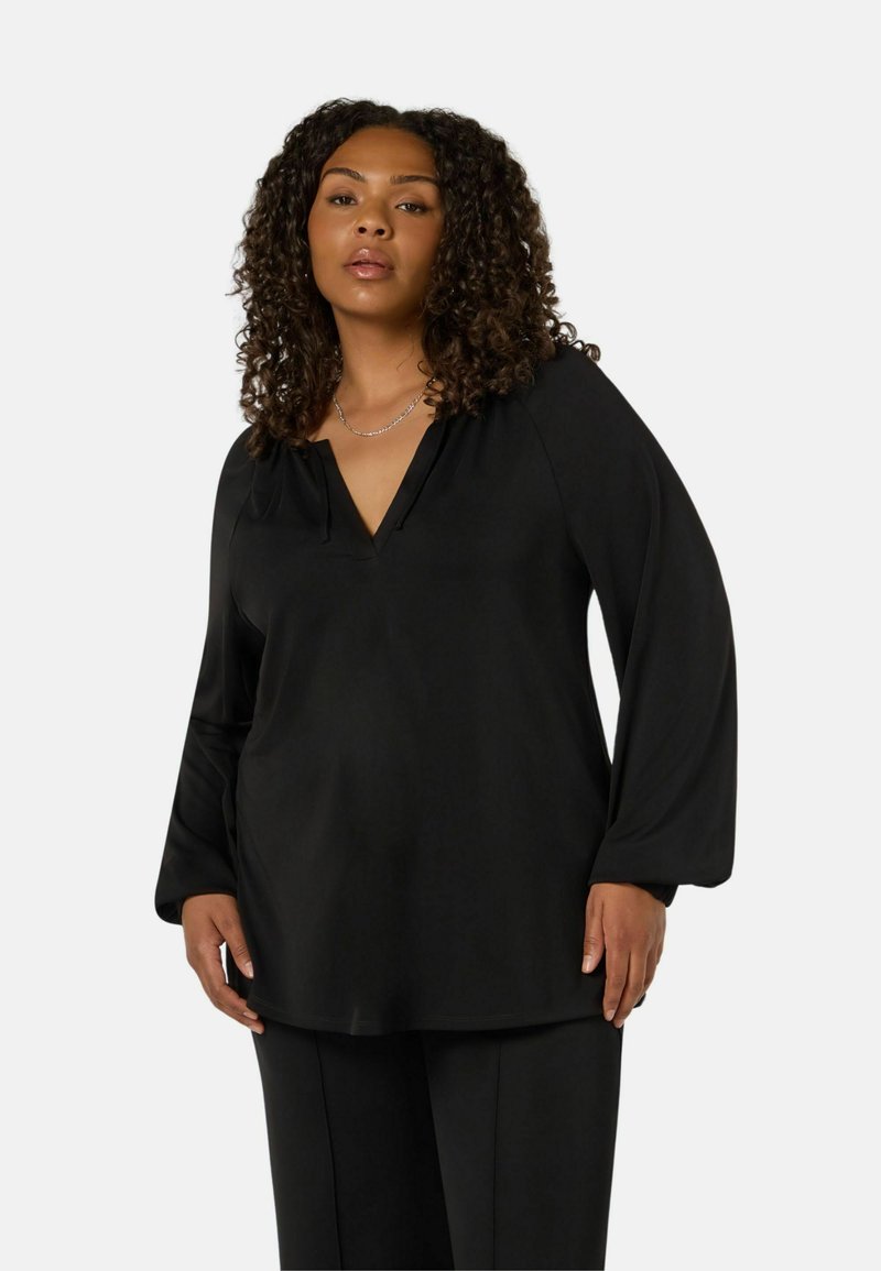 Musta pitkähihaisen paita V-kaula-aukolla, pehmeää kangasta, löysä istuvuus ja hienovarainen yksityiskohta kaula-aukossa. Yhdistetty vastaaviin housuihin.