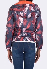 Hooded puffer jacket featuring a navy background with red and white leaf patterns. Elastic cuffs and a solid orange upper hood.