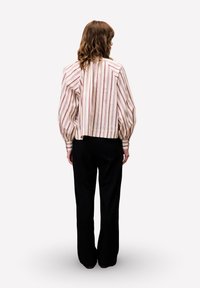 Gestreepte blouse in crème, roze en bordeaux, met pofmouwen en een cropped ontwerp, gecombineerd met zwarte wijde broek.