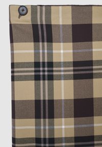 Tessuto a quadri beige, nero e bianco con un pulsante nero visibile nell'angolo in alto a sinistra, che mostra un primo piano dei dettagli del tessuto.
