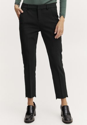 Black tailored pants with side pockets, tapered legs, and slits at the cuffs. Made from smooth fabric, styled with a fitted silhouette.