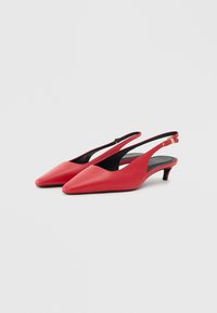 Punane nahast slingback kontsad terava ninaga ja väikese kitsaste kontsadega. Omab musta sisetald ja reguleeritavat pahkluu rihma.