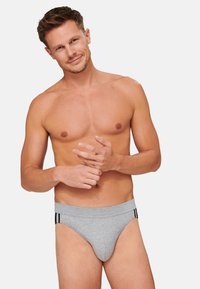Mutande grigie in cotone con una fascia elastica alta che presenta strisce nere. Il materiale appare morbido e il design è di tipo fitted a vita bassa.