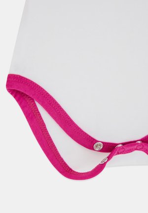 Nahaufnahme eines weißen Stoffs mit leuchtend pinkem Rand und Metall-Druckknöpfen entlang des Randes, die auf ein Kleidungsverschluss-Detail hinweisen.