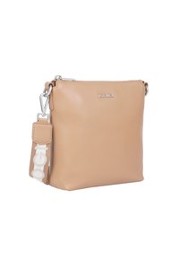 Tan läder crossbody-väska med texturerad yta, silverfärgad hårdvara och en avtagbar rem med en vit logotyp. Dragkedjestängning upptill.