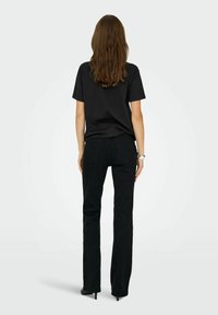 Zwarte t-shirt met korte mouwen in combinatie met zwarte skinny jeans, met een zachte textuur en een klassieke silhouet. Hakken accentueren de outfit.
