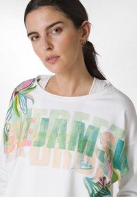 Witte sweatshirt met een kleurrijke bloemenprint en vetgedrukte tekst. Zacht materiaal met een losse pasvorm en wijde halslijn, met levendige accenten.