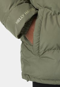 Zelená vatovaná bunda s kapsou na zip, elastickými manžetami a logem "Helly Hansen" v světlé barvě na rukávu.