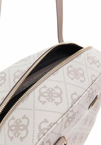 Sac fourre-tout gris clair avec un motif de logo texturé, fermeture éclair dorée et accents en cuir, mettant en valeur un intérieur noir spacieux.