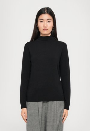 Musta pitkähihainen pooloneule pehmeästä materiaalista, jossa on slim fit -leikkaus ja ribbireunat, yhdistettynä harmaisiin ruutuhousuihin.