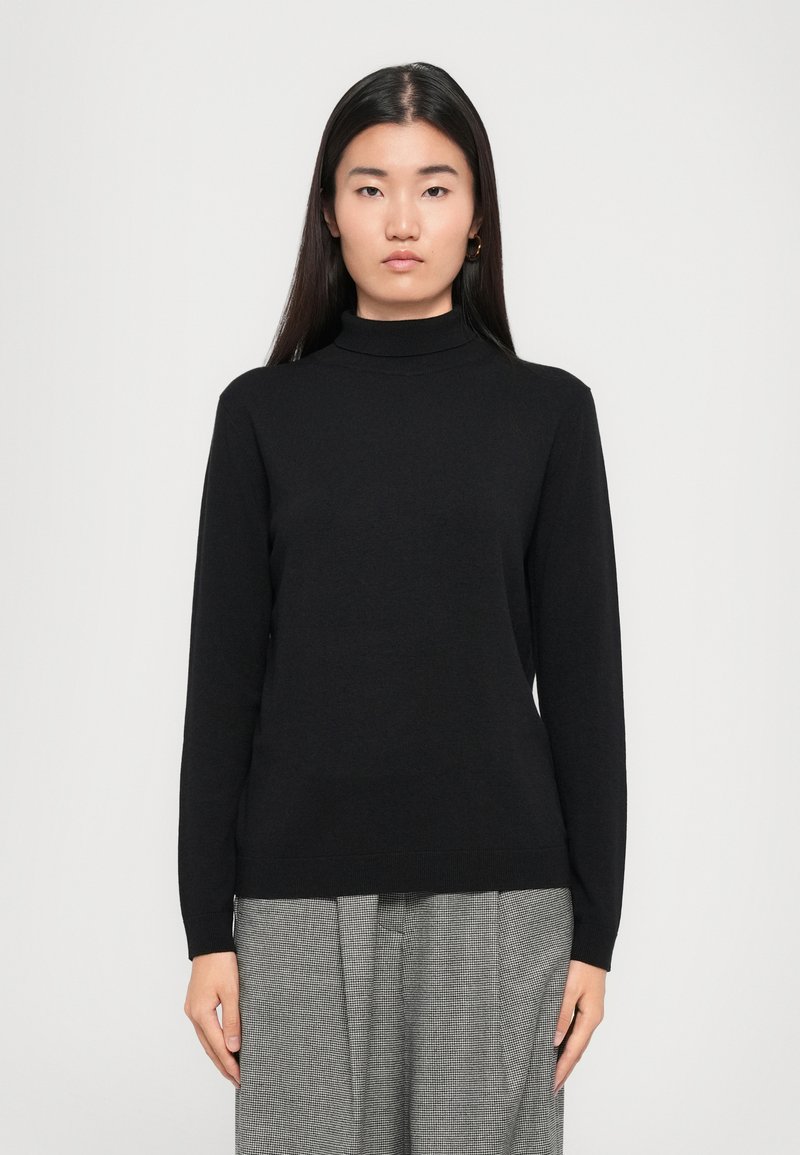 Schwarzer langärmeliger Rollkragenpullover aus einem weichen Material, mit einer taillierten Silhouette und gerippten Bündchen, kombiniert mit grauen karierter Hose.
