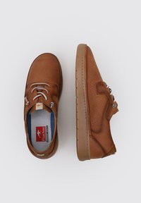 Zapatos de cuero marrón con un diseño perforado, cordones blancos en contraste y una suela texturizada. Logo visible en la plantilla.