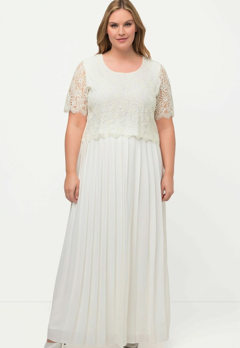 Vestido maxi blanco con un corsé de encaje con patrones florales, mangas cortas y una falda plisada. Tela suave con un diseño fluido.