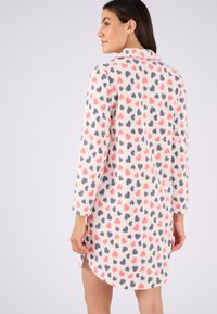 Accappatoio in pile, crema con motivo a cuori rosa e blu, maniche lunghe, colletto e spacchi laterali per facilitare i movimenti.