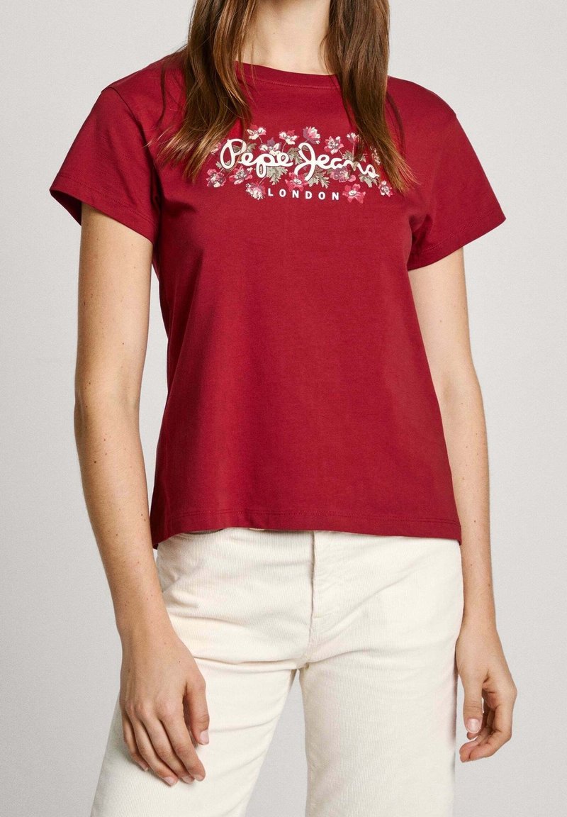Röd bomullströja med korta ärmar, med en blommönstring och "Pepe Jeans London"-text i vitt i mitten.