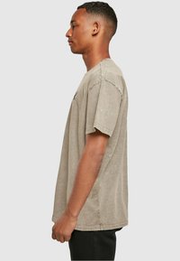 Light grey oversized T-shirt in soft fabric, featuring short sleeves and a relaxed fit. Visible stitching and subtle texture details.