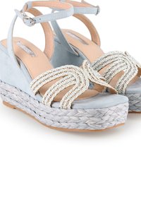 Sandalias de cuña de ante azul claro con correas trenzadas, detalles dorados y suela de yute tejida. Diseño de punta abierta con correa en el tobillo.