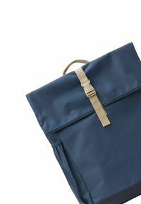 Mørkeblå rygsæk lavet af glat stof med en fold-over klap, beige spænde til stropperne og detaljer med sidelommer. Minimalistisk design uden mønstre.