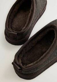 Sötétbarna slip-on papucsok puha plüss béléssel és szövetkülsővel, világos felületen elhelyezve.