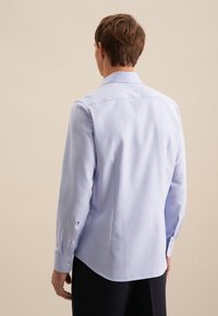 Camicia a maniche lunghe azzurro chiaro realizzata in tessuto intrecciato, con colletto, polsini abbottonati e vestibilità su misura. Texture liscia, senza fantasie.