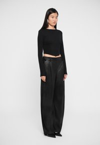 Black long-sleeve crop top with textured fabric, paired with high-waisted, wide-leg black trousers featuring a smooth finish and side detailing.