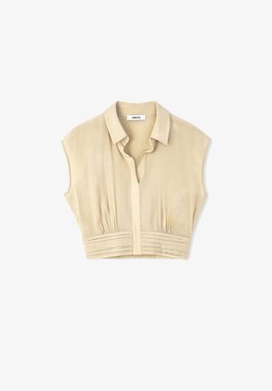 Blusina beige a vita alta realizzata in tessuto morbido, caratterizzata da un colletto, chiusura con bottoni e dettagli arricciati in vita.