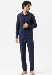 Ensemble de pyjama bleu marine comprenant un haut à boutons avec une poche poitrine et des manches longues, assorti à un pantalon ajusté. Tissu doux, coupe décontractée.