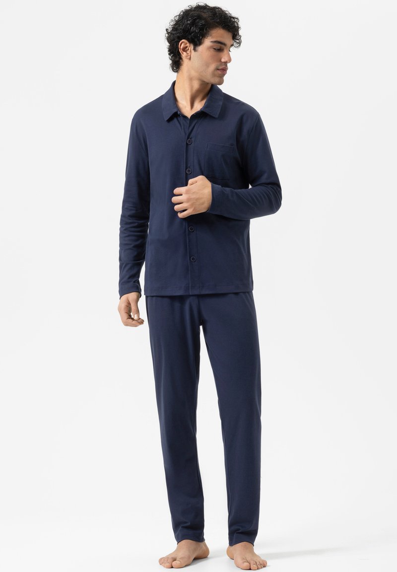Ensemble de pyjama bleu marine comprenant un haut à boutons avec une poche poitrine et des manches longues, assorti à un pantalon ajusté. Tissu doux, coupe décontractée.