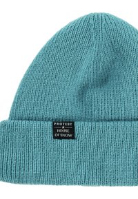 Teal gebreide beanie met een geribbelde textuur en een omgeslagen boord, voorzien van een zwart label met witte tekst: "PROTEST HOUSE OF SNOW."