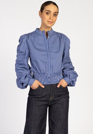 Blauwe en witte gestreepte blouse met pofmouwen, voorzien van een hoge kraag en knoopsluiting, gecombineerd met een donkere denim wijde broek.