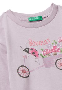 Jasnolawendowy bawełniany t-shirt z grafiką robaka na rowerku trójkołowym w otoczeniu kwiatów i grzybów. Napis „Bukiet” w kolorze różowym.