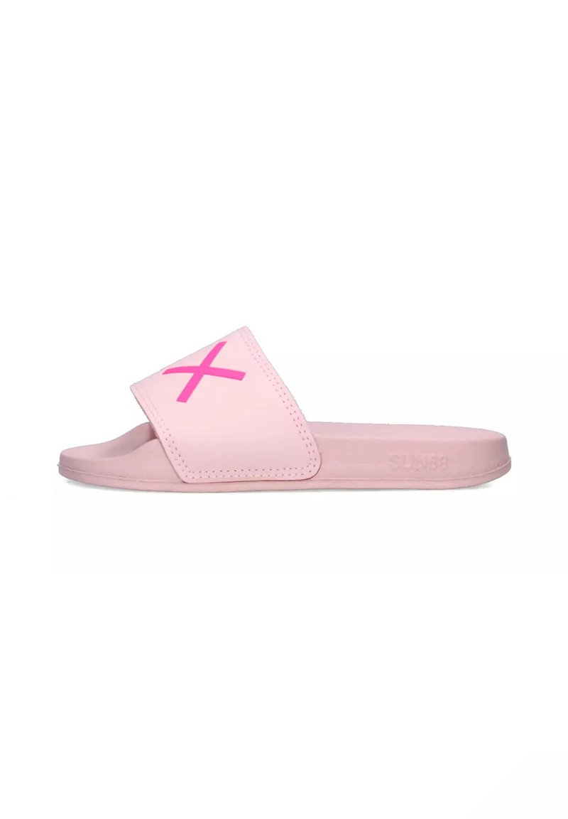 Sandal in rosa con una fascia ampia caratterizzata da un audace design a "X" rosa, materiale sintetico liscio, suola bassa e senza chiusure visibili.