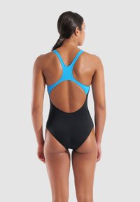 Maillot de bain une pièce noir avec un design de dos nageur bleu, présentant un dos ouvert et une texture lisse, adapté aux activités de natation.